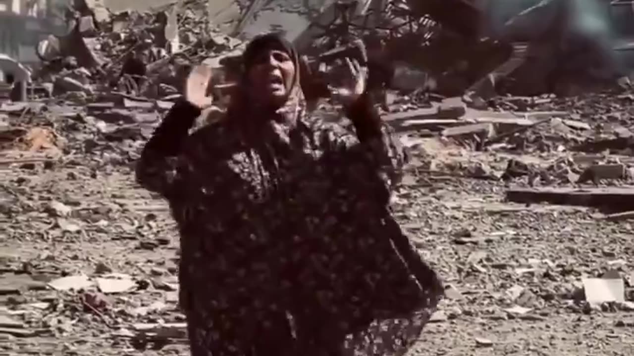 A Palestinian woman, standing amidst the ruins of her home