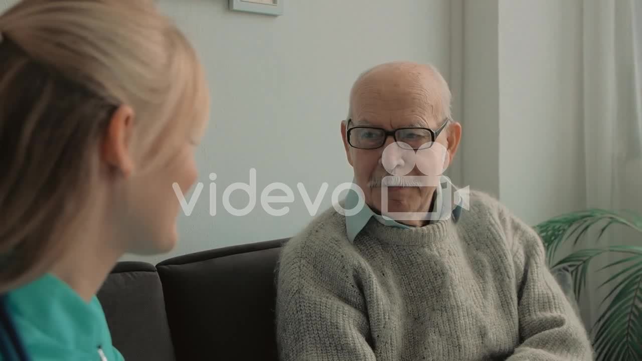 Elderly Man Talking With Young Caring Nurse