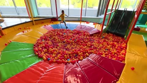 Sofia and a lot of colored balls on the Playground for kids