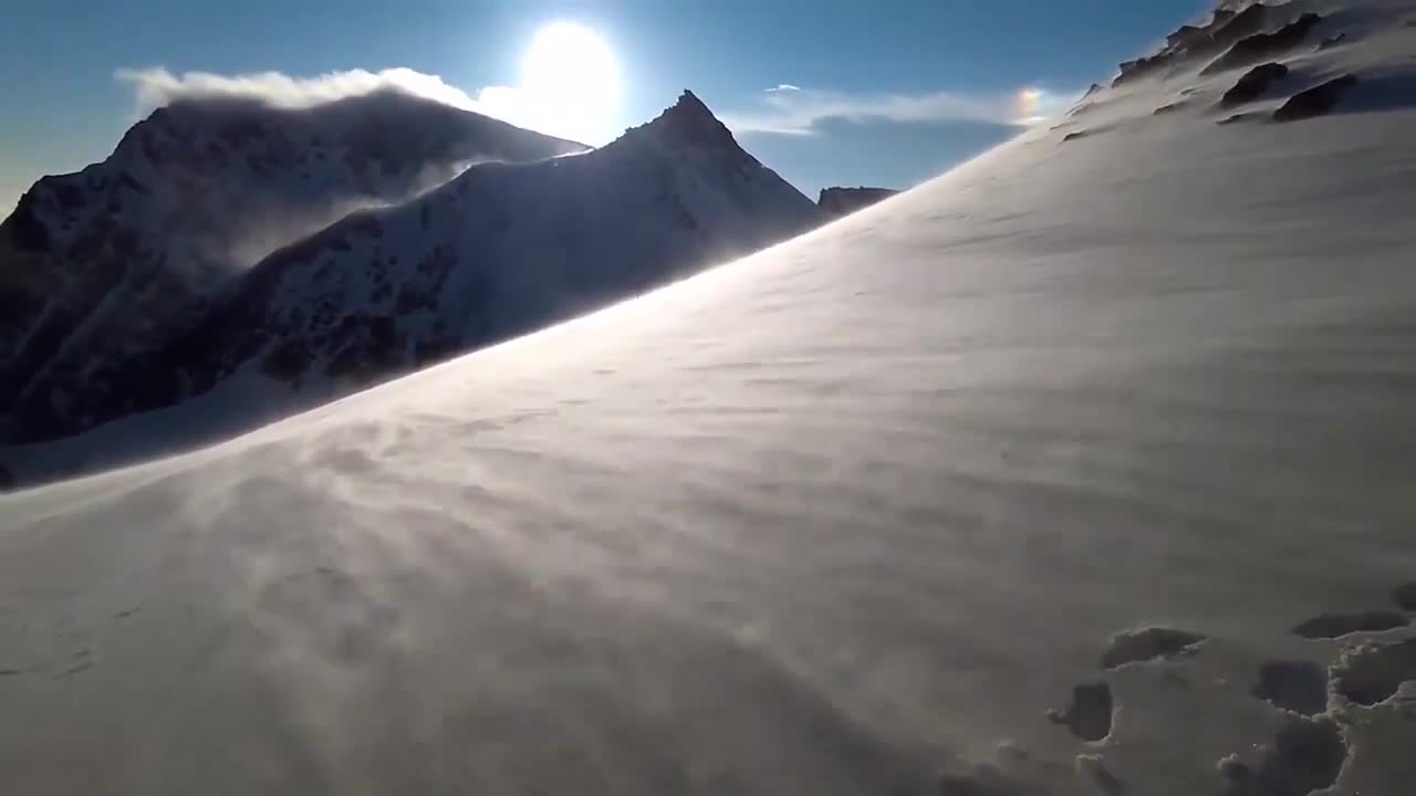 Group of Guys Enjoy Scenic View of Snowy Mountains Amidst Strong Winds