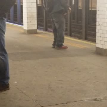 Man in all grey outfit dancing on subway platform
