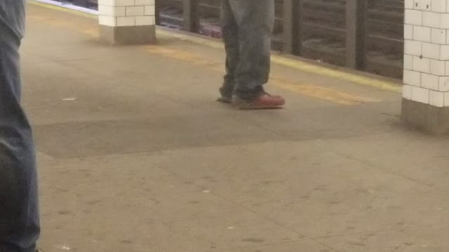 Man in all grey outfit dancing on subway platform