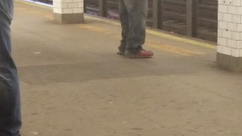 Man in all grey outfit dancing on subway platform