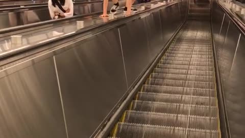 Girl trying to climb center part of escalator subway