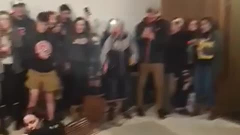11 black sweater elbow drops grey table off brown wall people cheer