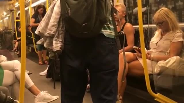 Man in green striped shirt playing flute on subway