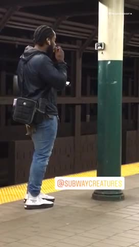 Man hangs phone on pillar in subway station