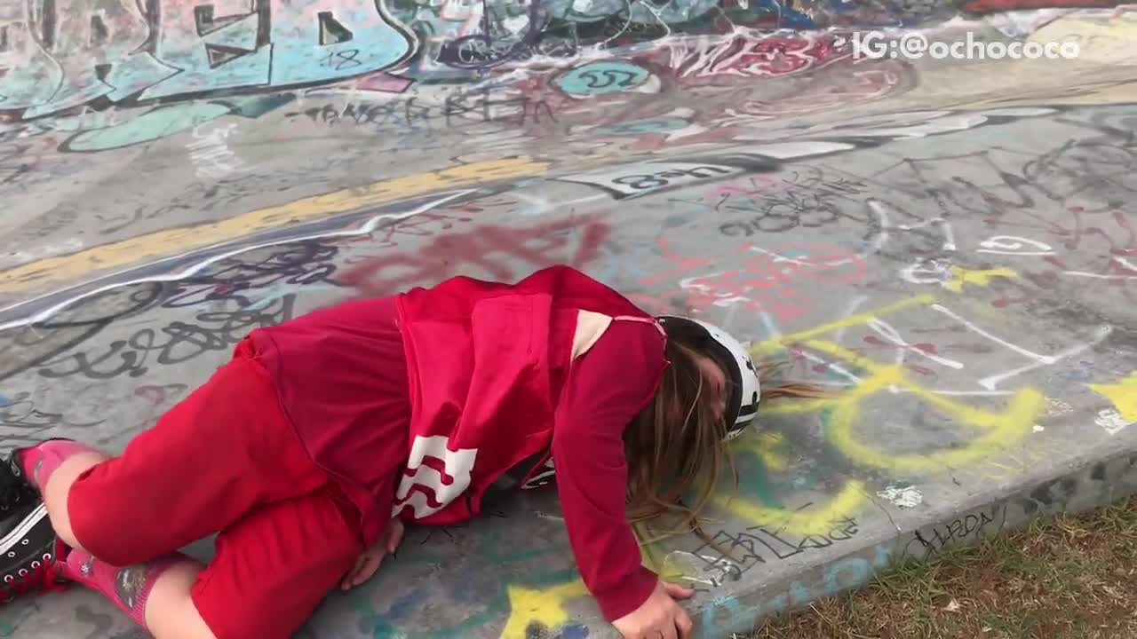 Girl in red outfit falls off skateboard