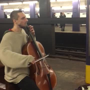 Man plays cello inside subway station, guys playing violin across station