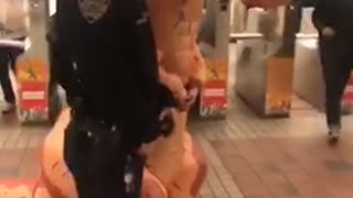 Nypd officers put handcuffs on guy in an orange inflatable t rex dinosaur suit and take a picture