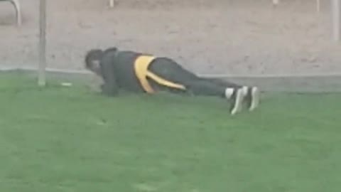 Guy doing planks pushups pelvic thrusting grass playground