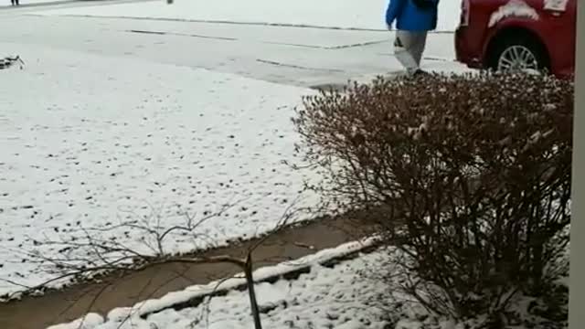 Lousy weather blue jacket guy walking down sidewalk slips on snow