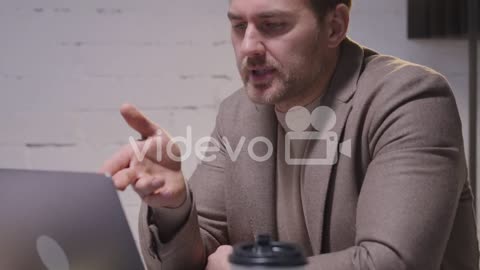 Serious Businessman Analyzing Data Using Laptop Computer During A Business Meeting