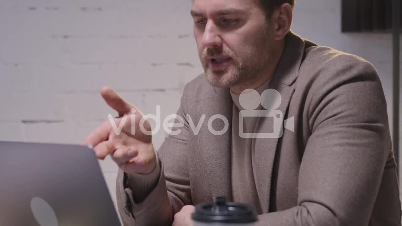 Serious Businessman Analyzing Data Using Laptop Computer During A Business Meeting