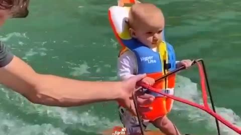 Cute little baby enjoying surfing in sea