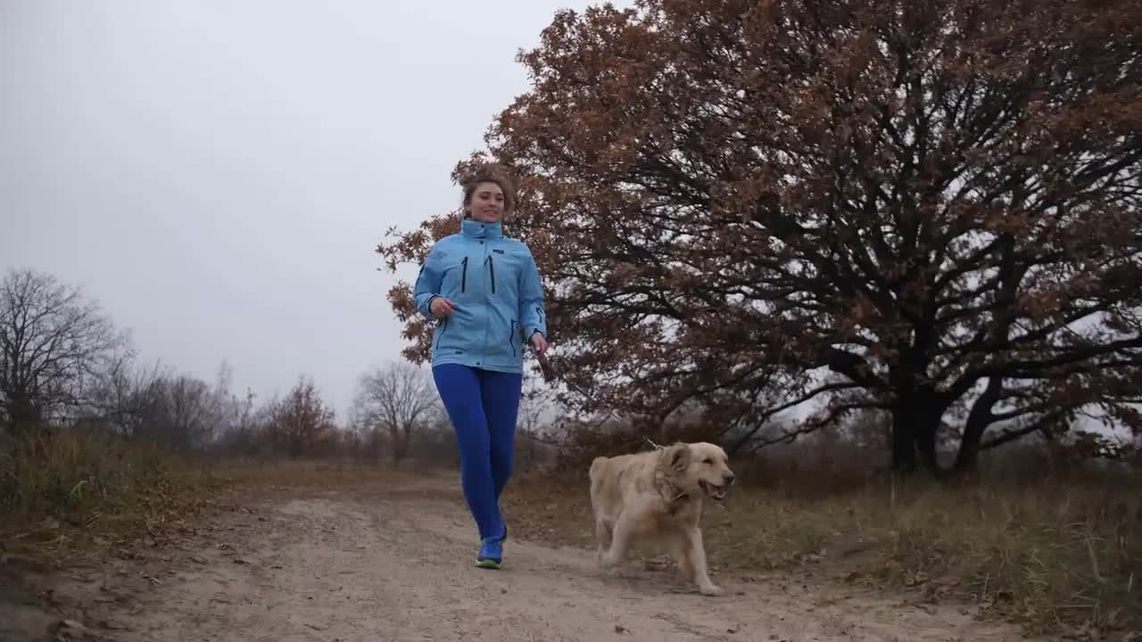 Positive attractive young sporty woman with her labrador retriever enjoying morning