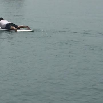 Two guys in the water laying down and paddling