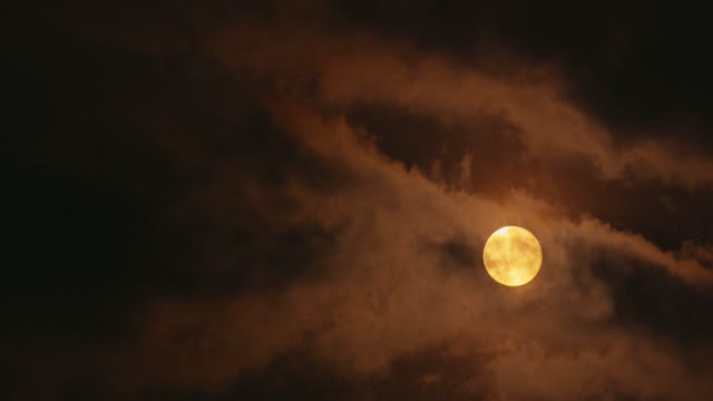 full-yellow-moon-shining-through-clouds