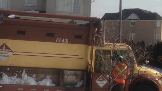 Garbage Man Shoveling Snow Into The Truck