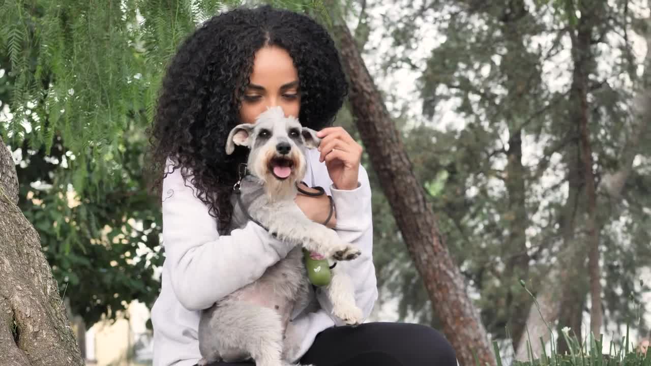 Young woman in a park carrying her schnauzer dog