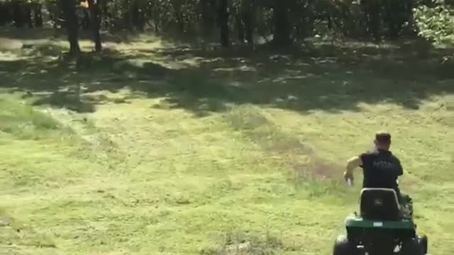Guy mowing grass gets beer tossed at him and drinks it