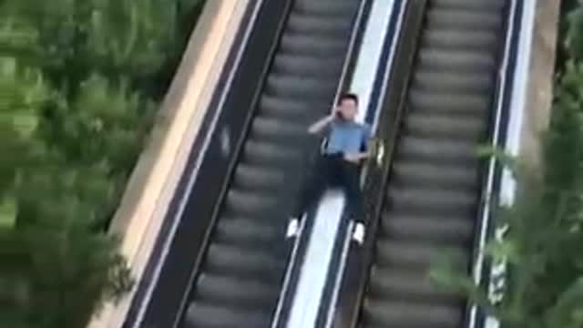 Guy Slides Down Escalator While Talking On Phone -