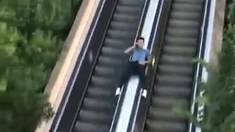 Guy Slides Down Escalator While Talking On Phone -