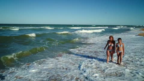 Mother and daughter talk and walk on the seashore