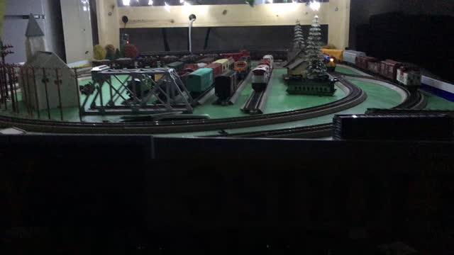 Three trains running around the layout at night with lights on the HO deck