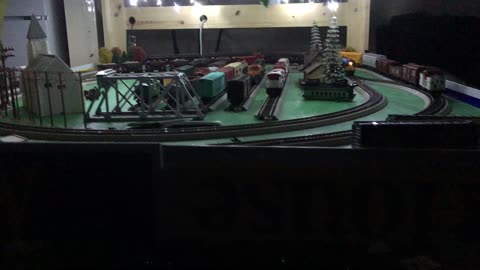 Three trains running around the layout at night with lights on the HO deck