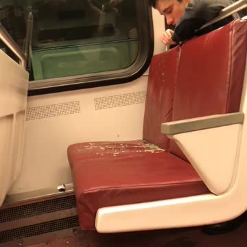Man throws up on red seat of train