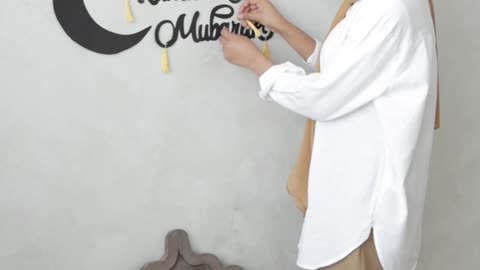 a-woman-sticking-ramadan-decoration-on-the-wall