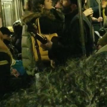 Guy sings and plays his guitar on subway