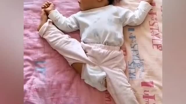 Toddler seen doing splits while sleeping in bed