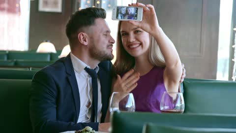 An Engaged Couple Taking A Video Of Themselves Using A Smartphone