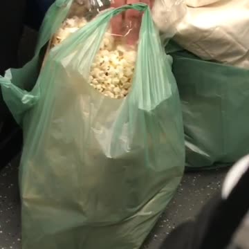 Woman eating popcorn from green bag