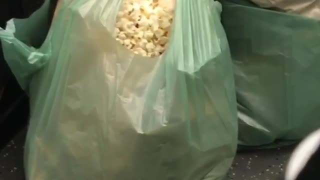 Woman eating popcorn from green bag