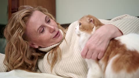 A Woman Petting Her Cat On The Bed