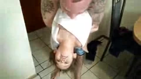 Toddler tries to look up while hanging upside down.