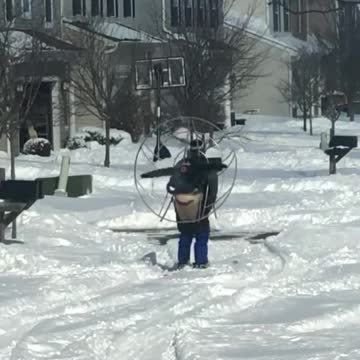 Heavy snow no match for guy wearing skis and high powered fan
