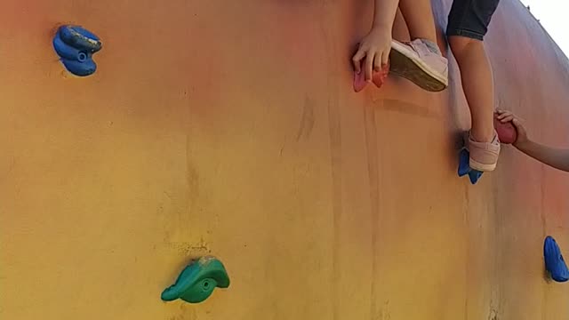 Girl climbing a rock wall in a playground