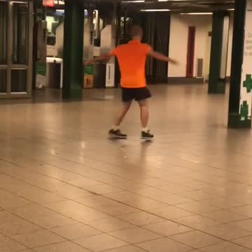 Guy orange shirt bald spinning in subway train station