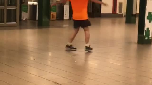 Guy orange shirt bald spinning in subway train station