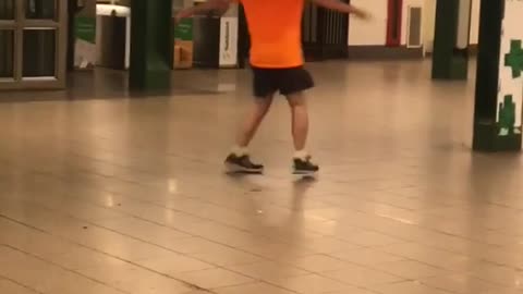 Guy orange shirt bald spinning in subway train station