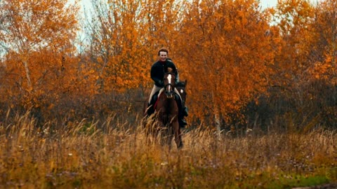 Two woman riding horses in the autumn field