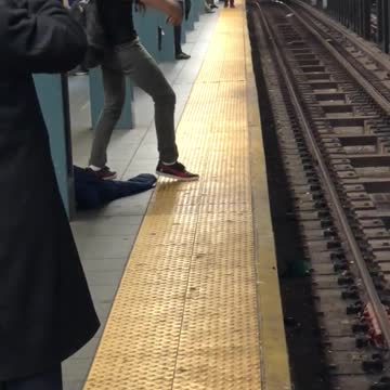 Man with long curly black hair sings on subway platform