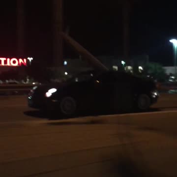 Black car with surfboard coming out of moonroof
