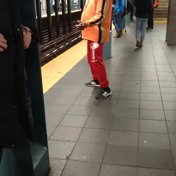 Man in orange air guitar on subway platform
