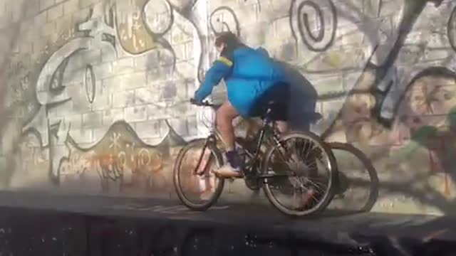 Blue jacket kid tries to ride bike off graffiti wall falls over handlebars