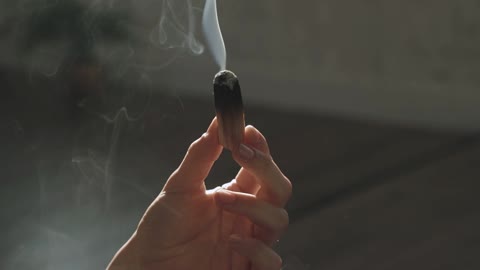 A Person Holding A Smoking Wooden Stick
